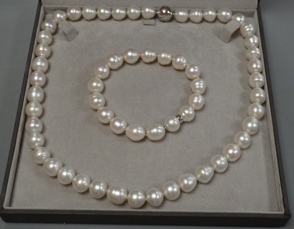A cased modern Australian Kailis single strand South Sea pearl necklace, 53cm and matching bracelet, 19cm, both with diamond set white metal (tests as 18ct) clasps, retailed by Musson.